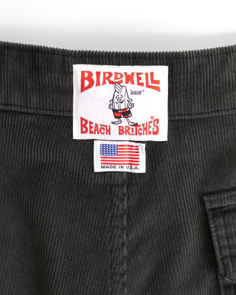 Close-up of the Birdwell Beach Britches label on the Classic Corduroy Shorts - Charcoal, showing a cartoon bird, the American flag, and MADE IN U.S.A. text, with classic styling and an adjustable drawcord waist.