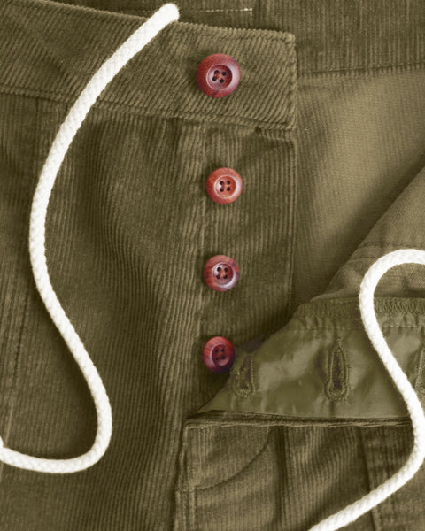 Close-up of the Classic Corduroy Shorts - Fatigue in olive green, featuring a white adjustable drawcord waist and four brown buttons—one left unbuttoned to reveal the inside pocket lining—highlighting their timeless retro fit.