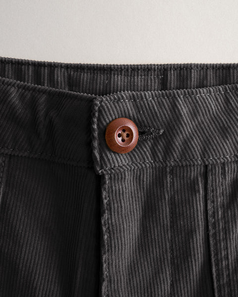 Close-up of the waistband and brown button on Classic Corduroy Pants - Charcoal, featuring dark charcoal corduroy fabric.