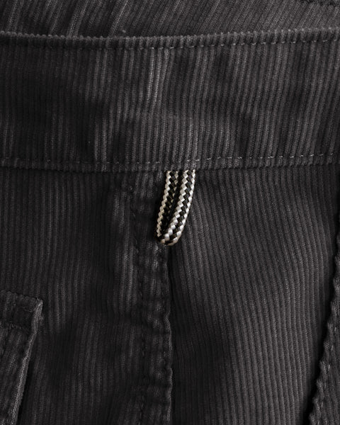 Close-up of charcoal Classic Corduroy Pants in 100% cotton, showing the fabric texture and a small patterned loop attached to the waistband.