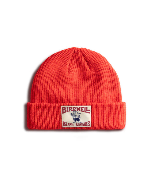 Red License Plate Watchcap featuring a wide ribbed fisherman style with a rectangular license plate patch containing Birdwell Beach Britches text and a cartoon character illustration.