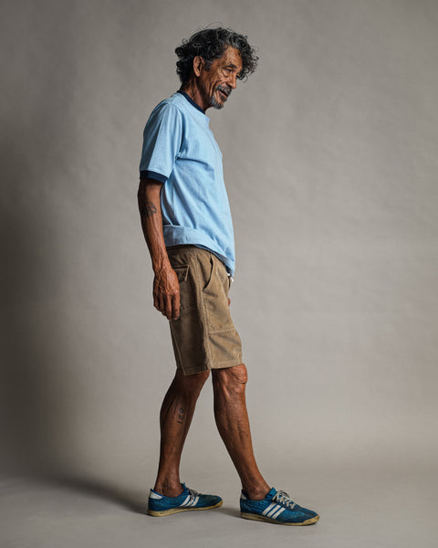A man in profile wears a light blue t-shirt and Classic Corduroy Shorts - Sand with a drawcord waist.