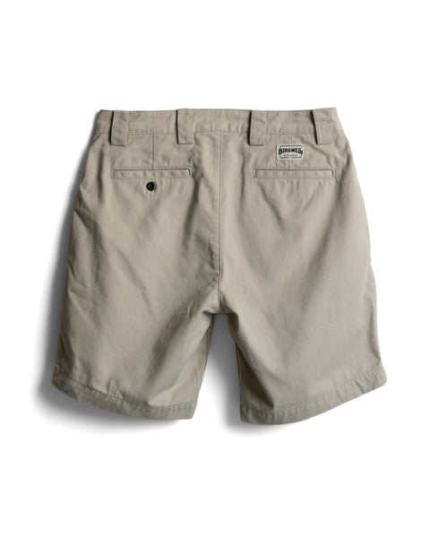 Back view of beige Stockman Chino Shorts - Bone, featuring two button-closure back pockets and a rectangular logo patch above the right pocket.