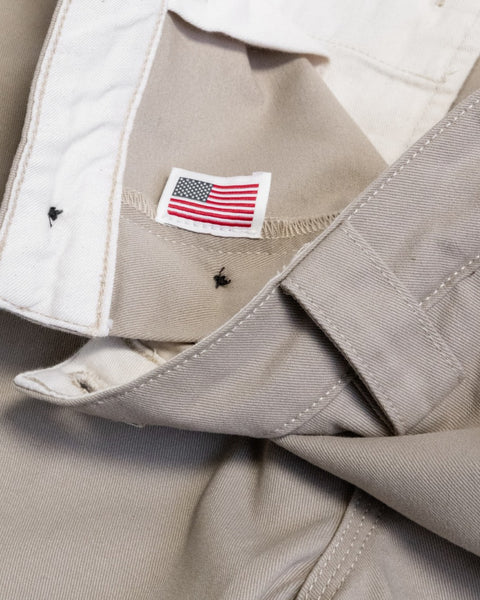 Close-up of the interior waistband of Stockman Chino Shorts - Bone, featuring a small American flag label sewn into the light tan cotton twill back seam.