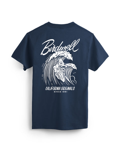 Back of navy t-shirt featuring a graphic of birdie mascot surfing on a wave in white. Text featuring “Birdwell” and “California Originals Since 1961.”