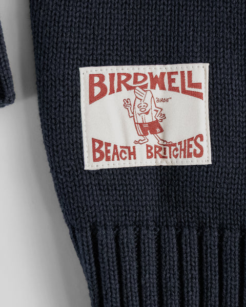 Close-up of a label on a dark knitted item with 'Birdwell Beach Britches' text and logo.