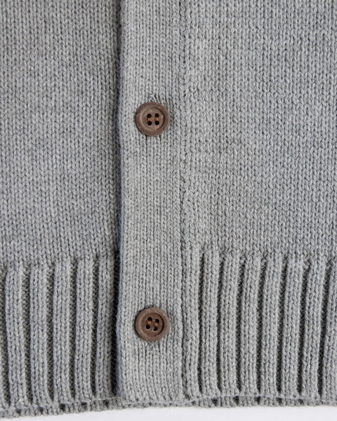 Close-up of a gray knitted cardigan with brown buttons on a white background