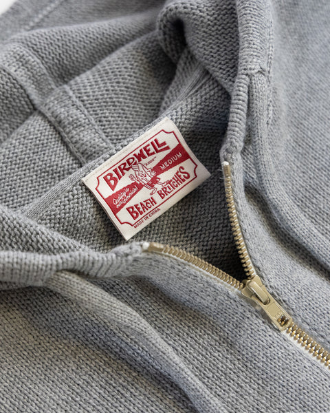 Gray hoodie with a brand label on a close-up of the fabric and zipper.