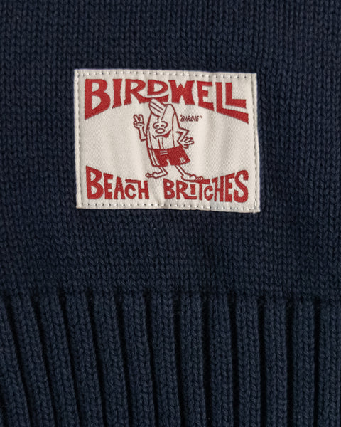 Close up detail of the license plate label in bone and red. Navy fabric.