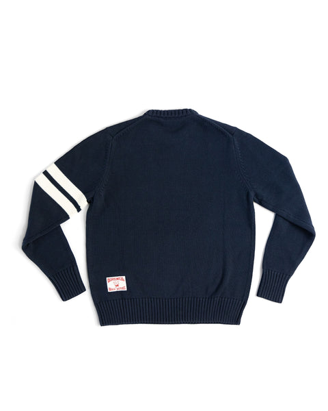 Back View of the Comp Stripe Sweater in Navy with two bone stripes on the left arm. Product on white background. License plate label on bottom left corner.
