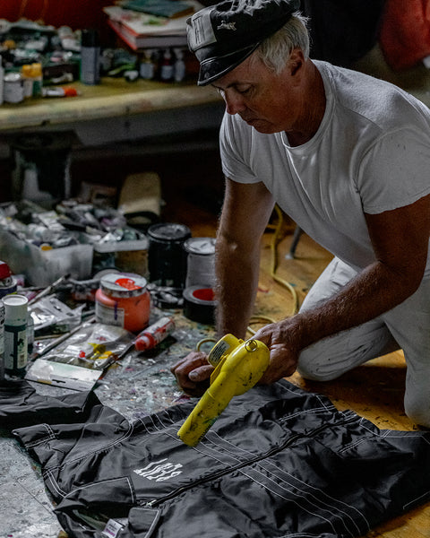Brian Bent holding a yellow hand dryer while drying the screenprint on the jacket.