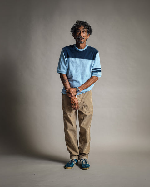 A man wears a Special Teez Champ - Arctic Blue/Navy color-blocked T-shirt with khaki pants and blue sneakers.