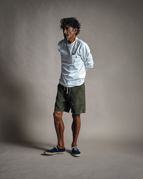 Man wearing a High Tee Pocket Long Sleeve - Vintage White, styled as a white crewneck pocket t-shirt with olive green shorts.