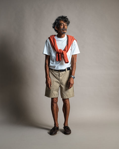 A man wearing a white t-shirt, khaki shorts, and dark shoes, with a Harmony Hoodie - Paprika draped over his shoulders.