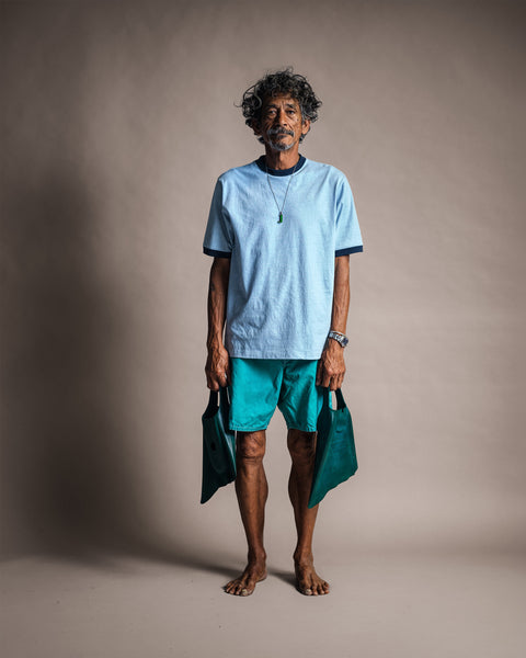 A man standing and holding swim fins while wearing a Special Teez Ringer - Arctic Blue/Navy light blue ringer t-shirt and teal shorts.