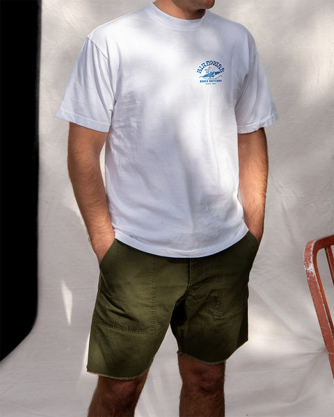 Person wearing a white t-shirt with Surfin' Birdie Screenprint in blue and green shorts against a plain background