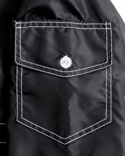Close-up of a black jacket pocket with white stitching on a white background