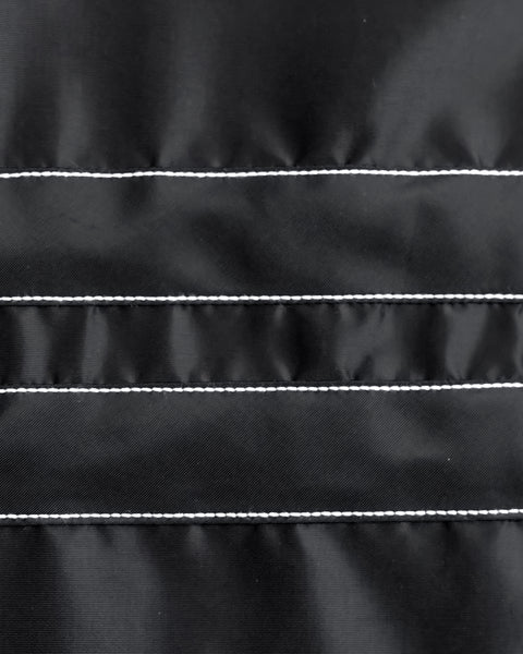 Close-up of black fabric with two horizontal stripes with white stitching details