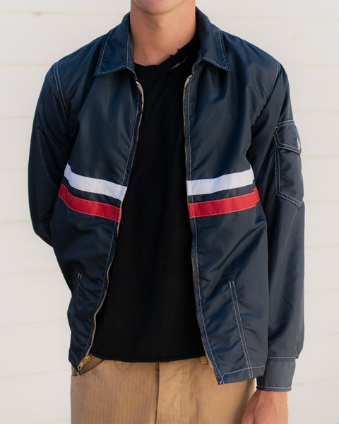 Model wears the Comp Jacket in Navy with Red and White stripes across the center. 
